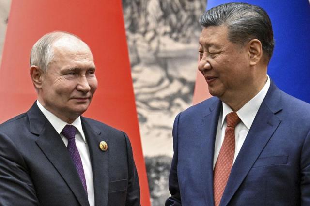 Chinese President Xi Jinping right and Russian President Vladimir Putin look toward each other as they shake hands prior to their talks in Beijing China on May 16 2024 AP-Yonhap