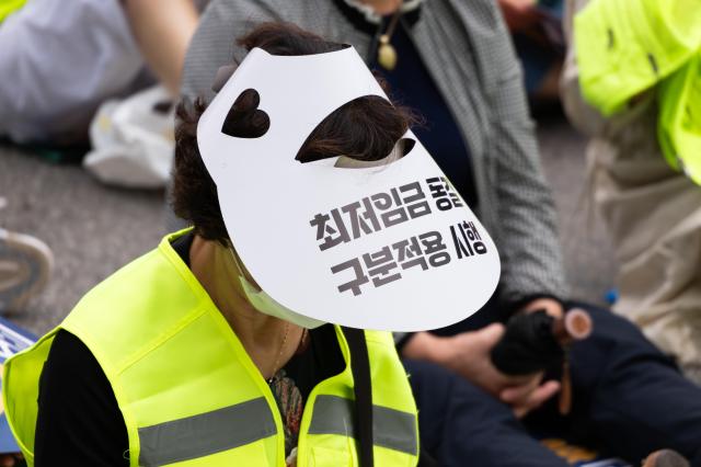 Participant wears hat with slogans at minimum wage reform rally National Assembly Seoul June 25 2024 AJU PRESS Park Jong-hyeok