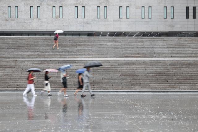 Pedestrians rush past Seoul Art Center in central Seoul amid heavy rainfall on July 2 2024 AJU PRESS Park Jong-hyeok
