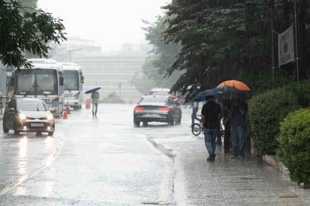 Pedestrians with umbrellas pass by the Yonhap News Agency building near Gwanghwamun during heavy rainfall in central Seoul on July 2 2024 AJU PRESS Park Jong-hyeok