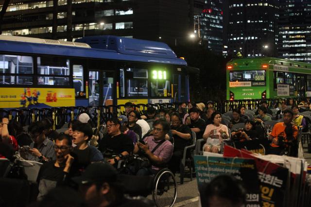 Buses pass behind protesters during the Move Toward Parade organized by SADD in front of the National Assembly on July 1 2024 AJU PRESS Han Jun-gu