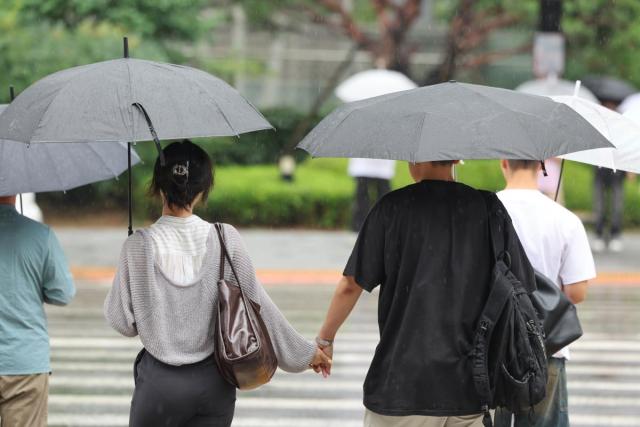 전국 곳곳에 장맛비가 내린 8일 오후 서울 용산역광장 인근에서 한 커플이 각자 우산을 쓰고 손을 잡은 모습 사진연합뉴스

