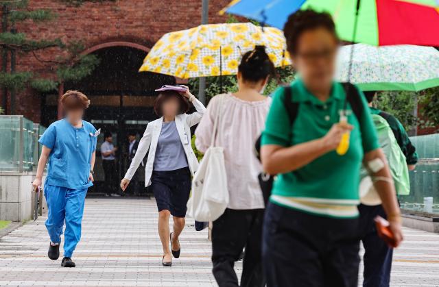 지난 7월 10일 오후 서울 종로구 서울대병원에서 의료관계자들이 갑자기 내린 소나기에 서류나 손으로 머리를 가린 채 급하게 이동하고 있다 사진연합뉴스