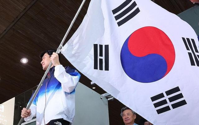 Koo Bon-gil the flag bearer for the South Korean team competing in the Paris Olympics enters the arrivals hall on Saturday at Charles de Gaulle Airport in Paris France carrying the Korean national flag