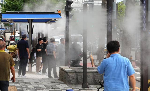 지난 22일 부산 동구 부산진역 앞 횡단보도 인근에 시민들이 쿨링포그인공안개 분사시설 아래를 지나며 더위를 식히고 있다 사진연합뉴스