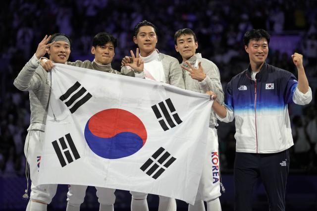 South Korean fencers Oh Sang-uk Gu Bong-il Park Sang-won and Do Gyeong-dong celebrate with their coach after winning the mens team sabre final match against Hungary during the 2024 Summer Olympics at the Grand Palais Wednesday July 31 2024 in Paris France AP-Yonhap