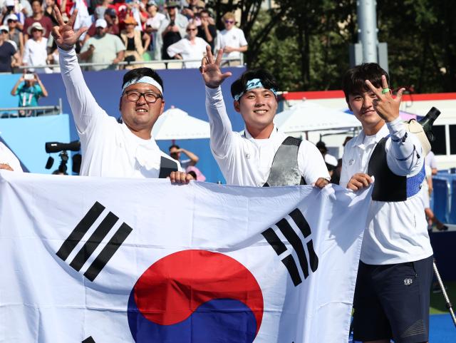 Kim Woo-jinL Lee Woo-seok and Kim Je-deok unfurl the South Korean flag after winning the mens team archery final at the Paris Olympics in France July 30 2024 Yonhap