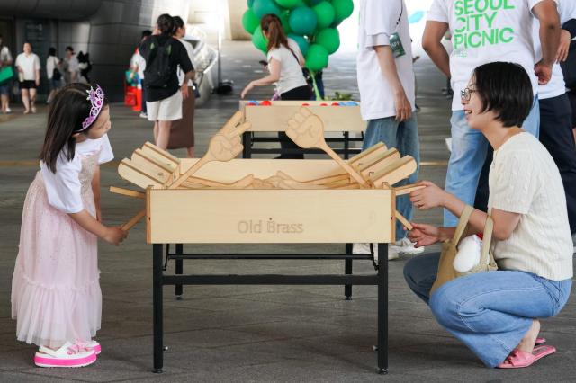 A child plays a wooden table game with parents at the 2024 Seoul City Picnic which opened on Aug 1 at the DDP in Seoul AJU PRESS Park Jong-hyeok