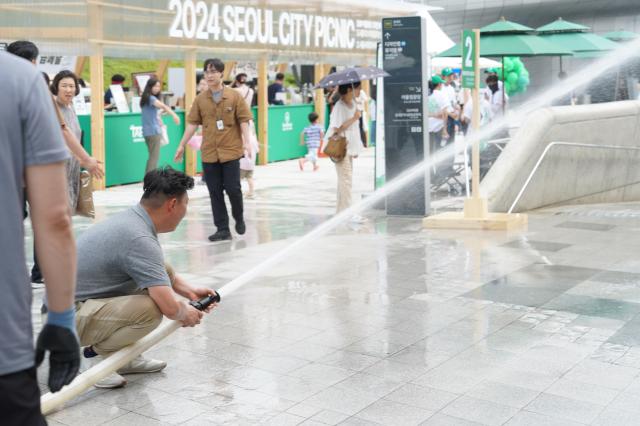 DDP workers spray water on the ground to beat the heat at the 2024 Seoul City Picnic which opened on Aug 1 at the DDP in Seoul AJU PRESS Park Jong-hyeok