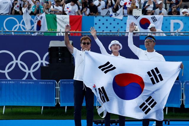 Kim Woo-jin right and Lim Si-hyeon center celebrate with their coach after winning mixed team final match against Germanys Michelle Kroppen and Florian Unruh at the Paris Summer Olympics Friday Aug 2 2024 Reuters-Yonhap