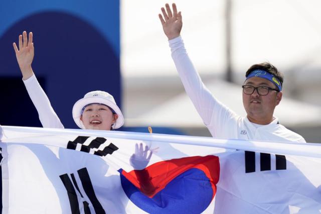 Archers Lim Si-hyeon left and Kim Woo-jin wave after winning gold in the mixed team event at the Summer Olympics in Paris France on Aug 2 2024 AP-Yonhap