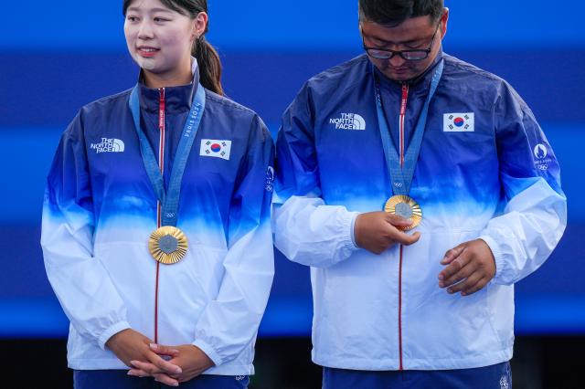 Gold medalists Lim Si-hyeon and Kim Woo-jin stand on the podium after winning the archery mixed team final match at the Paris Summer Olympics Friday Aug 2 AP-Yonhap