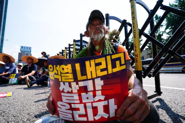 A farmer holds a placard demanding President Yoon Suk Yeols resignation and guaranteed rice prices during a rally organized by the National Farmers Federation on Aug 6 2024 AJU PRESS Park Jong-hyeok