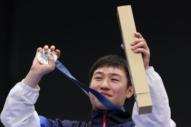 Silver medallist South Koreas Cho Yeongjae reacts on the podium during the victory ceremony for the 25m Rapid Fire Pistol mens Final during the Paris 2024 Olympic Games at Chateauroux Shooting Centre on August 5 2024 AFP-Yonhap