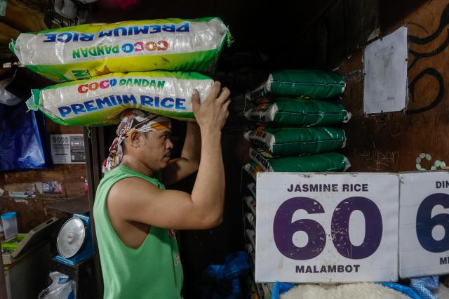 A merchant transporting bags of rice to a booth in a Quezon City marketplace located in Metro Manila Philippines Yonhap