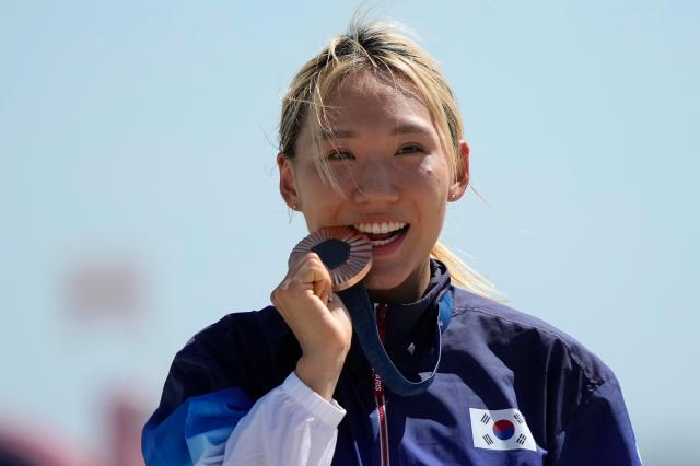 South Koreas Sung Seung-min bites her bronze medal on the podium after the womens individual modern pentathlon at the Paris Summer Olympics Sunday Aug 11 AP-Yonhap