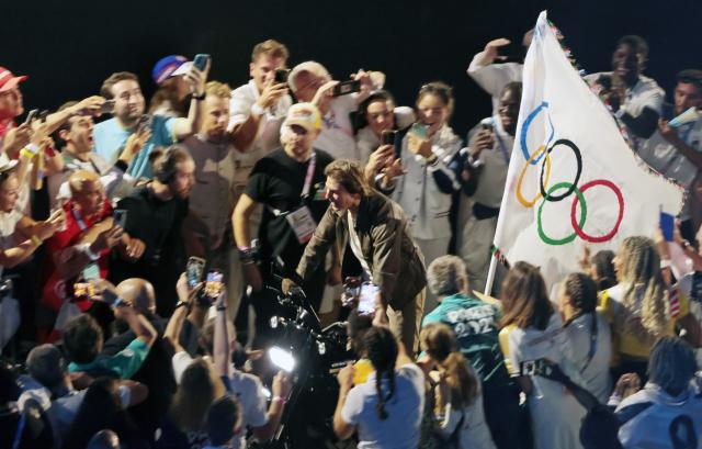 Actor Tom Cruise carries the Olympic flag on a motorcycle leaving Stade de France for Los Angeles during the Paris Olympics closing ceremony on Aug 11 2024 UPI-Yonhap