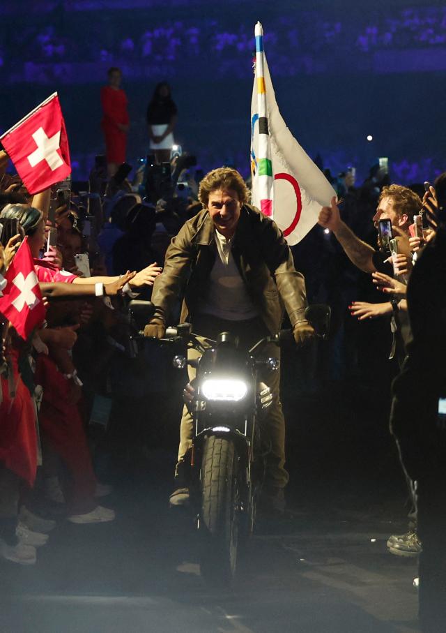 Actor Tom Cruise carries the Olympic flag on a motorcycle leaving Stade de France for Los Angeles during the Paris Olympics closing ceremony on Aug 11 2024 UPI-Yonhap