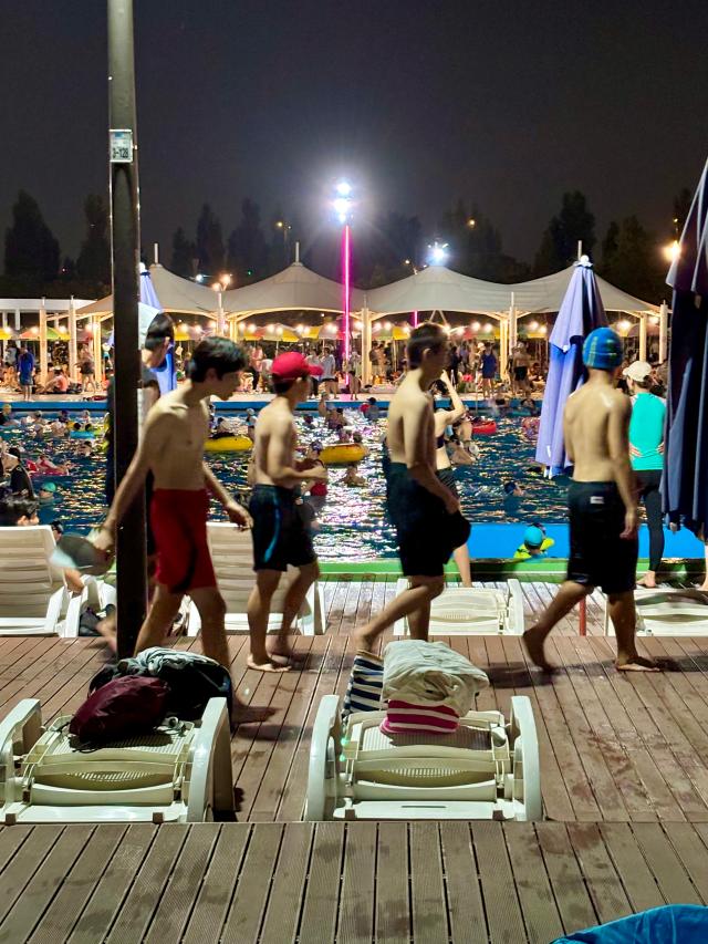 People walk past sunbeds at the swimming pool in Han River Park Yeouido Seoul on August 9 2024