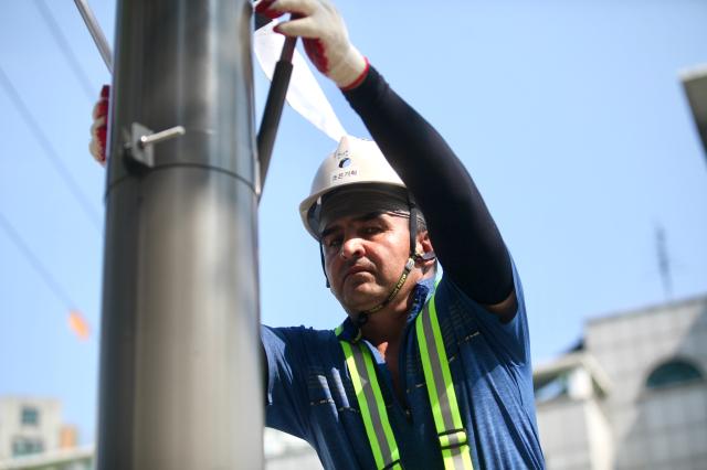 A worker hangs the national flag of Korea on a utility pole in Jongno-gu Seoul ahead of Liberation day of Korea on August 14 2024 AJU PRESS Han Jun-gu