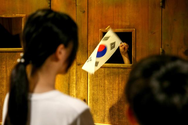 A visitor waves the national flag of Korea while experiencing the narrow room torture exhibit at Seodaemun Prison in Seoul on Aug 14 2024 AJU PRESS Kim Dong-woo