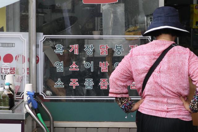 A customer looks at a sign promoting various foods including soju with dog meat at Moran Market in Seongnam Korea on July 24 AJU PRESS Han Jun-gu