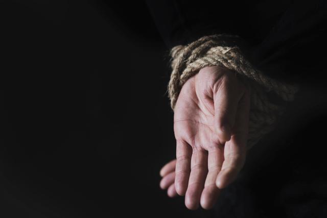 A man with his hands tied behind his back Getty Images Bank