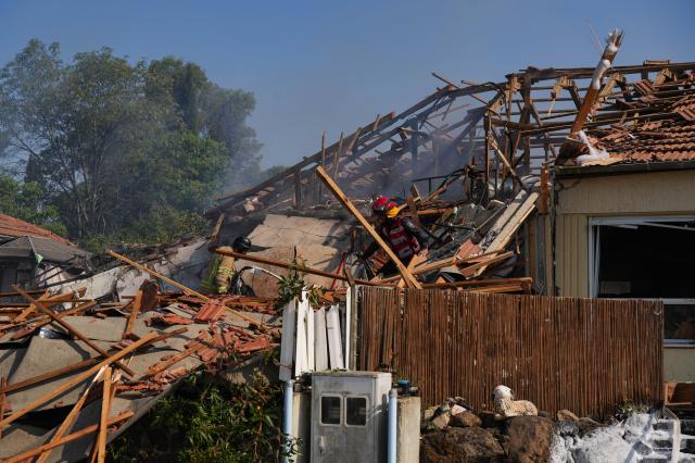 
Israeli emergency service members work at a house in Katzrin located in the Israeli-annexed Golan Heights that was directly struck by a rocket from Lebanon on Aug 21 2024