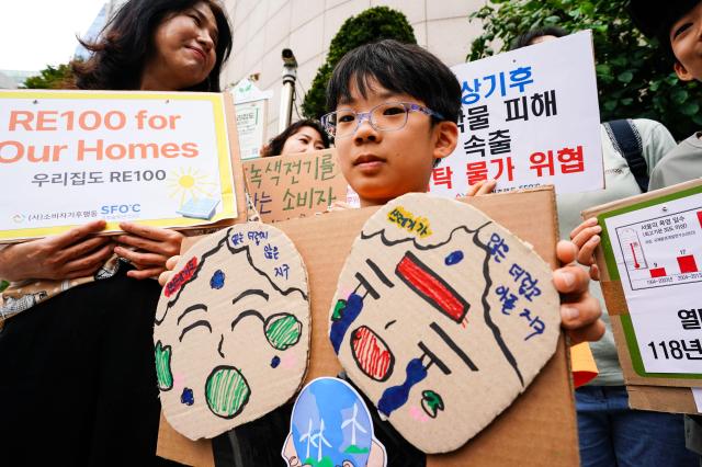 A boy attending the press conference holds a sign about the climate crisis outside Korea Electric Power Corps Seoul headquarters in Jung-gu Seoul Aug 22 2024 AJU PRESS Park Jong-hyeok