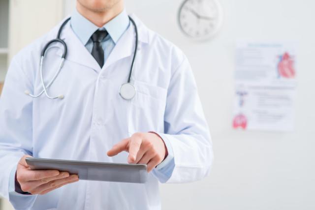 A man in doctors gowns pointing at his clipboard Getty Images Bank