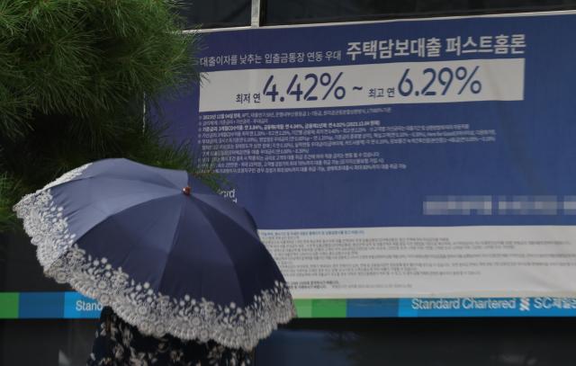 A pedestrian walks past a mortgage loan advertisement in Seoul on Aug 25 Yonhap