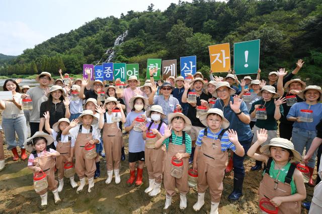 현대모비스 임직원과 가족 지역주민들이 충북 진천군 초평면 미르숲 입구에서 미호종개를 방류하는 모습 사진현대모비스