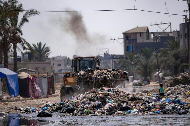 A bulldozer clears plastic and other debris from a street in central Gaza Strip on Aug 27 2024