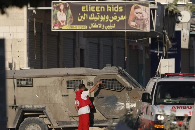 A Red Crescent rescue worker communicates with Israeli troops positioned outside Nur Shams camp near Tulkarem in the Israeli-occupied West Bank during an Israeli army raid on Aug 28 2024 AFP-Yonhap