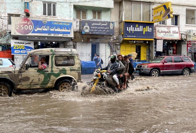 People ride a motorcycle through a flooded street during heavy rains in Sanaa Yemen on Aug 28 2024