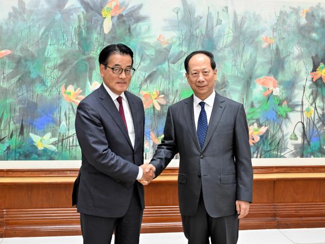 This is a photo of Constitutional Democratic Party of Japans secretary general Katsuya Okada left shaking hands with head of the United Front Work Department of the Communist Party of China Shi Taifeng Aug 29 2024 Xinhua - Yonhap