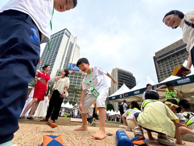 A child plays ttakjichigi traditional Korean game where players flip folded paper toys at the 2024 Seoul Market in Seoul Plaza on Sep 2 2024 AJP Han Jun-gu