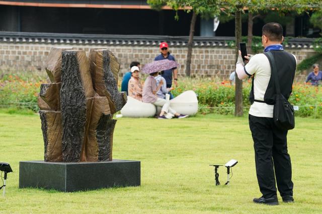 A visitor takes a picture of the sculpture Vitality of Earth by Kim Yun-shin at the Seoul Sculpture Festival in Songhyeon Green Plaza Jongno District Seoul Monday Sept 2 2024 AJP Park Jong-hyeok