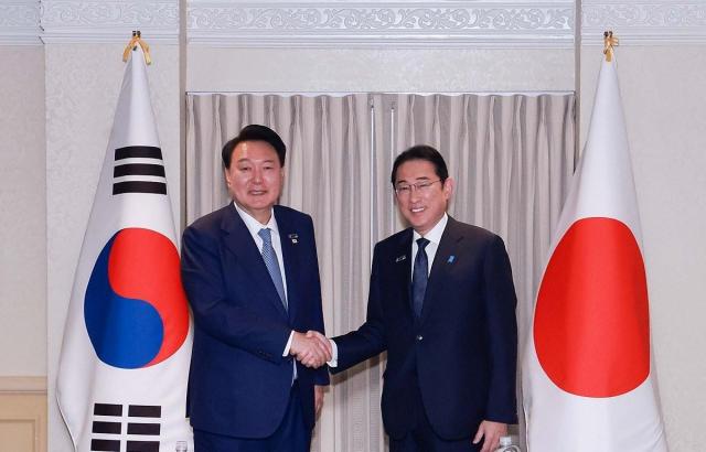 President Yoon Suk Yeol and Japanese Prime Minister Fumio Kishida shake hands at the summit held in Washington DC on July 10 Yonhap