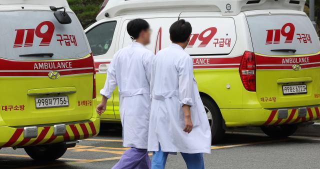 Doctors walk past parked ambulances at a hospital in Daegu Sept 6 2004 Yonhap