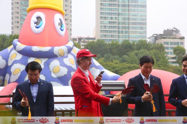 Philip Colbert takes a photo of lobster claw-shaped scissors at the opening ceremony of the public art project Lobster Wonderland at Seokchon Lake Seoul Sept 6 2024 AJP Han Jun-gu