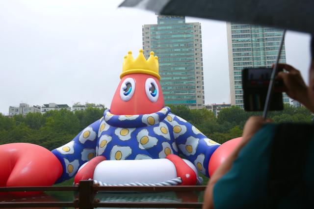 A person takes a photo of the Floating Lobster King art balloon at the public art project Lobster Wonderland at Seokchon Lake Seoul Sept 6 2024 AJP Han Jun-gu