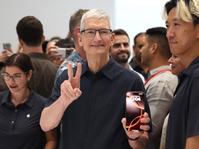 Apples CEO Tim Cook examines the latest iPhone 16 model at the companys special event held at its Cupertino California headquarters on September 09 2024 AFP-Yonhap