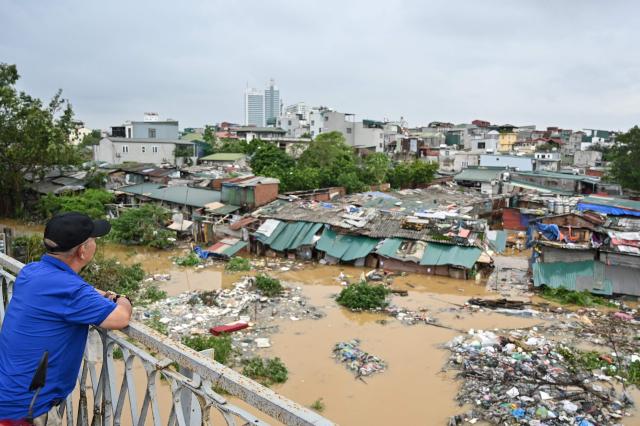 This photo shows a man on Long Bien Bridge surveying Hanois flood-ravaged neighborhoods below September 10 2024 AFP-Yonhap