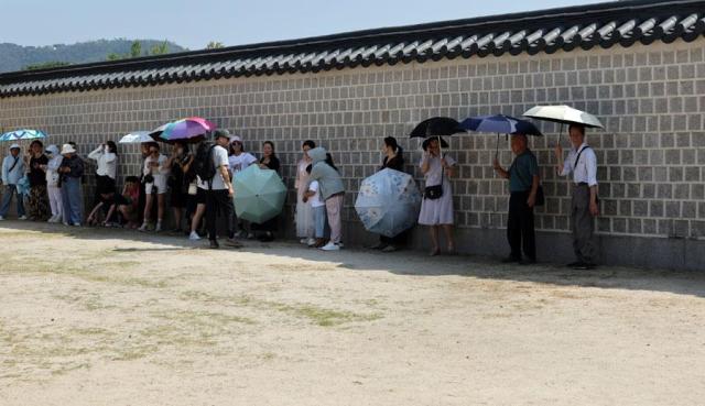 Tourists seek respite from the heat along the walls of Gyeongbokgung Palace in central Seoul on Sept 11 2024 Yonhap