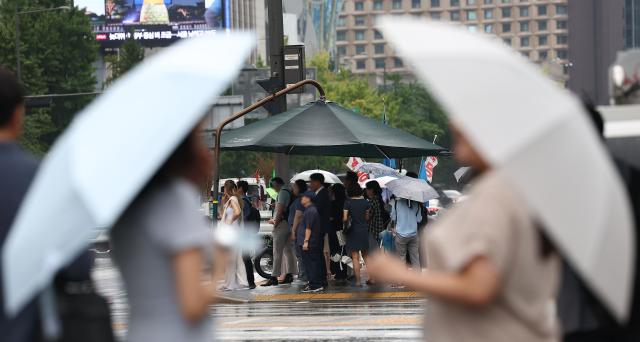 지난 5일 오후 비가 내리는 서울 광화문광장에서 시민들이 비를 피해 햇빛 가림막 아래서 보행 신호를 기다리고 있다  사진연합뉴스