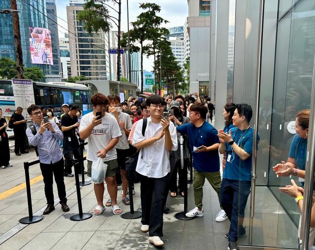 20일 오전 서울 중구 명동 애플 스토어 앞 국내 자급제 1호 구매자인 김민재씨28가 직원들의 박수를 받으며 매장에 들어서고 있다 사진김민우 기자