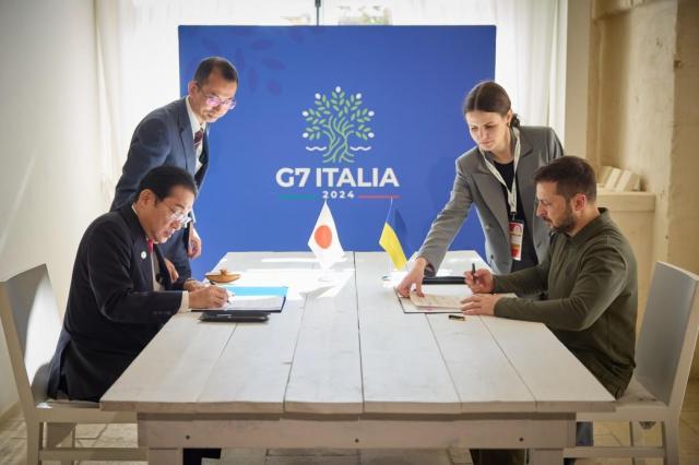 Japans Prime Minister Fumio Kishida bottom left and Ukrainian President Volodymyr Zelenskyy signs a security agreement in the G7 Summit June 13 2024Courtesy of Ukraines Presidential Office