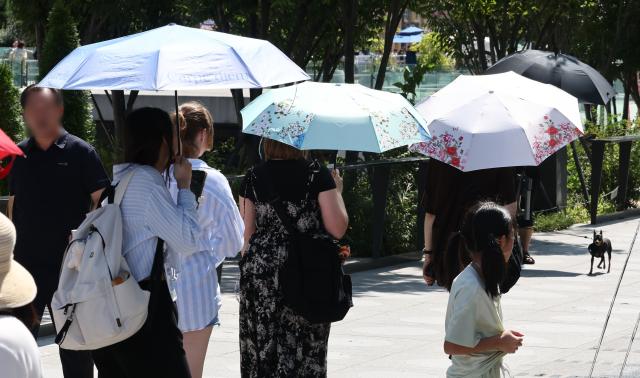 지난 16일 서울 종로구 광화문광장에서 외국인 관광객들이 양산을 쓰고 걸어가고 있다 사진연합뉴스