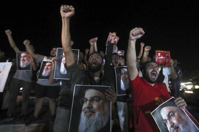 Lebanese and Palestinian men hold portraits of Hezbollah leader Sayyed Hassan Nasrallah as they shout slogans during a protest in the southern port city of Sidon Lebanon on Sept 28 2024 AP-Yonhap